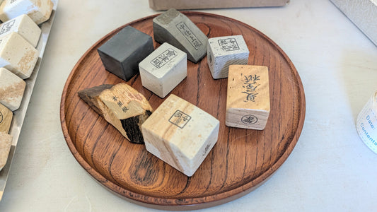 A wooden plate containing several types of tomo nagura whetstones.